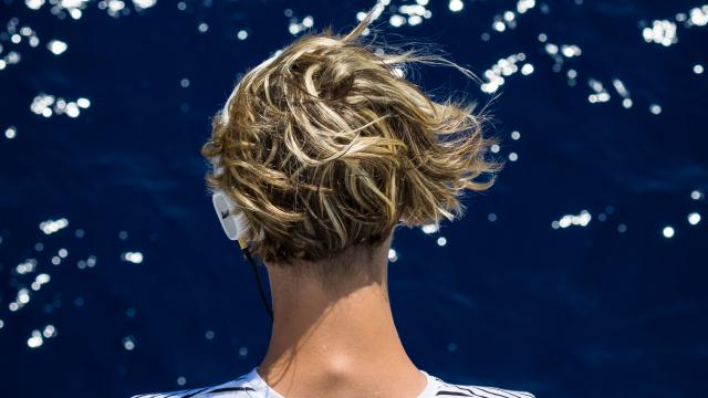 Homme écoutant de la musique en tricot rayé devant la mer