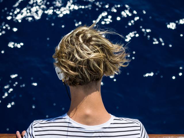 Homme écoutant de la musique en tricot rayé devant la mer