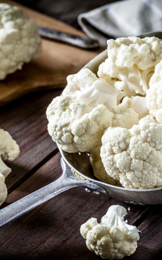 Fresh organic cauliflower in an old metal colander shot on rustic wooden table. This vegetable is considered a healthy salad ingredient. Predominant colors are white and brown. Low key DSRL studio photo taken with Canon EOS 5D Mk II and Canon EF 100mm f/2.8L Macro IS USM